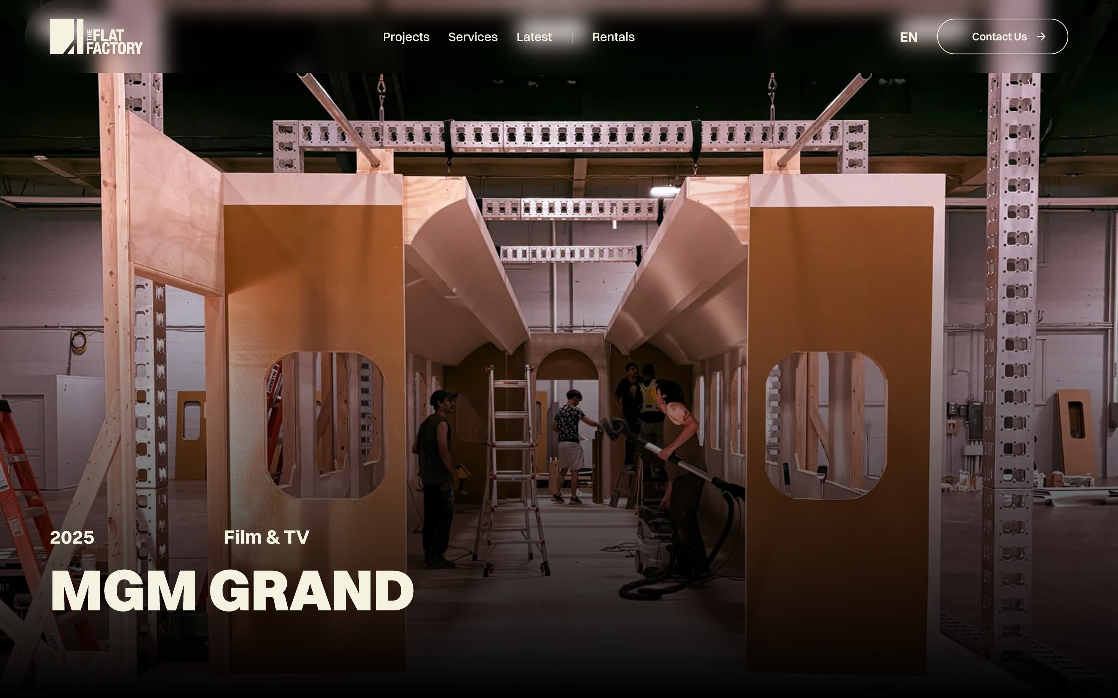 theflatfactory.ca, the MGM Grand project page: a train car set half built on the shop floor inside a box truss, crew at work, under the title MGM Grand